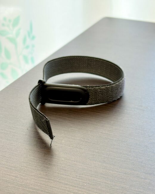 机の上にループ状に置かれたGoogle Fitbit Airのナイロンバンドと本体