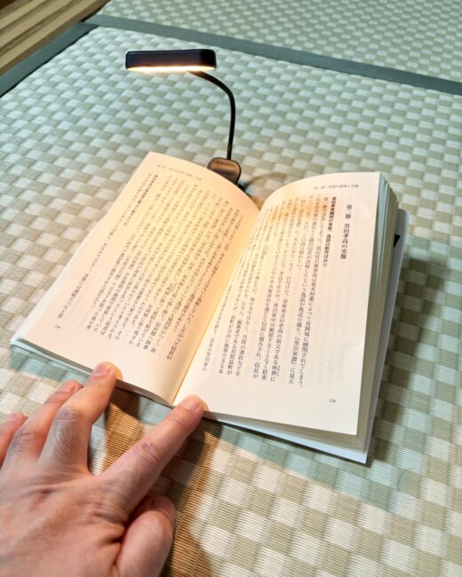 小型の読書灯が、畳の上で開いた本の手元だけを照らしている