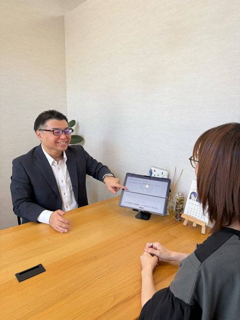 タブレットに映した企画書を指しながら、講師のChanさんと話す酒井