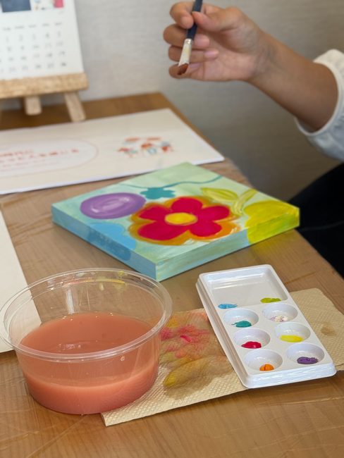 花の絵を描き進めるキャンバスと、絵の具を出したパレット