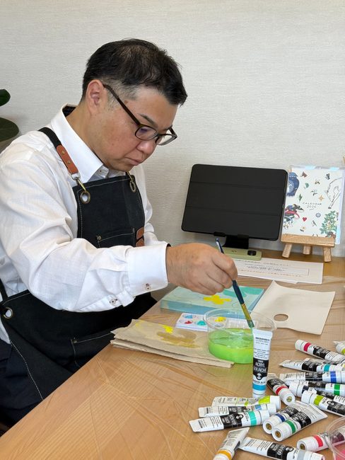筆を持ち、キャンバスに色を塗る酒井